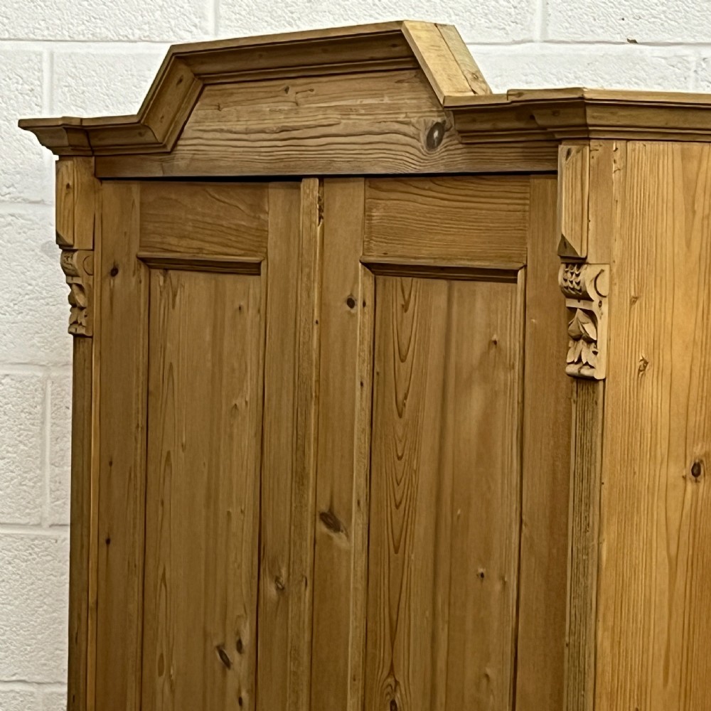 A tall Victorian pine two-door cupboard featuring field-panelled doors, turned bun feet, and a shaped bonnet top pediment. View IV
