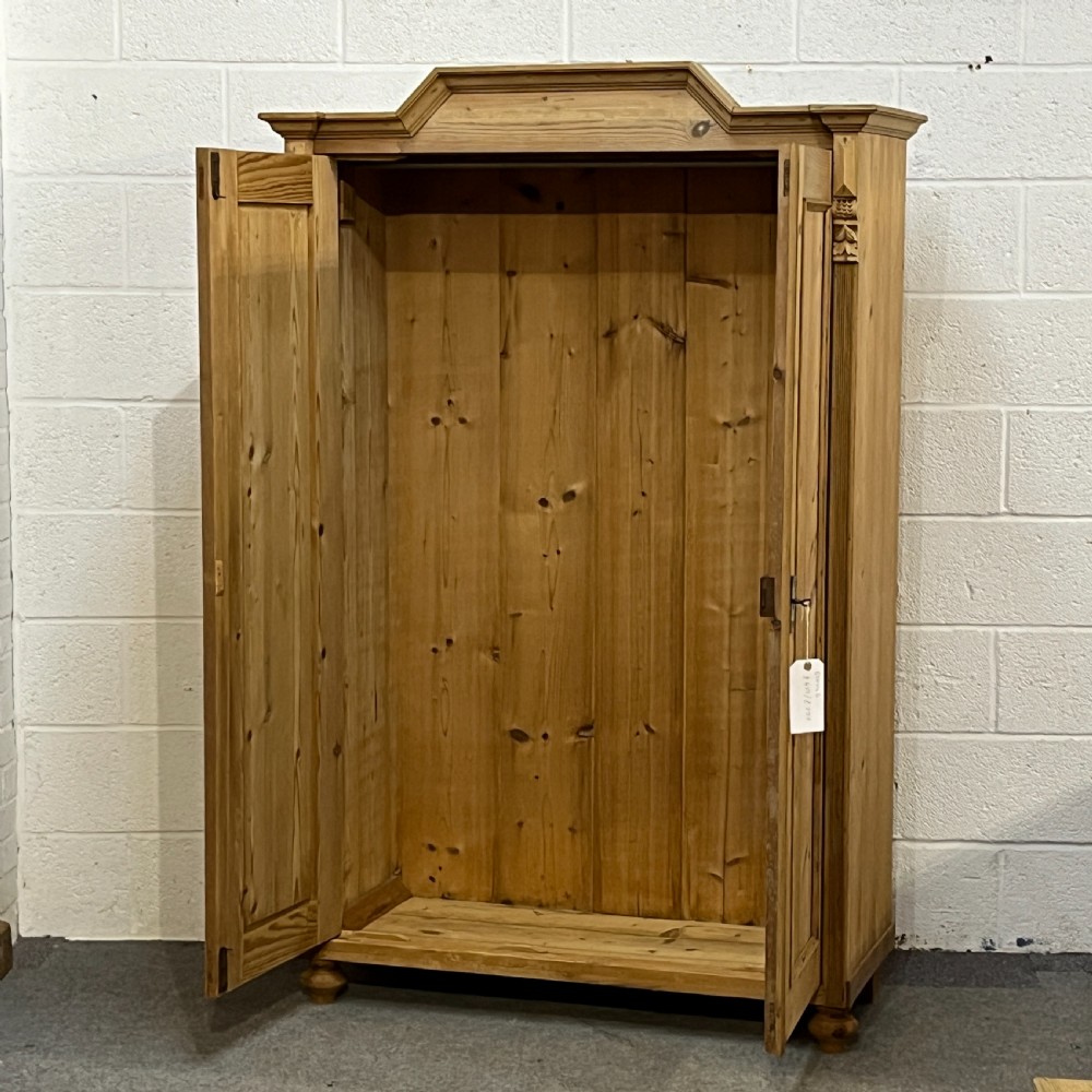 A tall Victorian pine two-door cupboard featuring field-panelled doors, turned bun feet, and a shaped bonnet top pediment. View VI