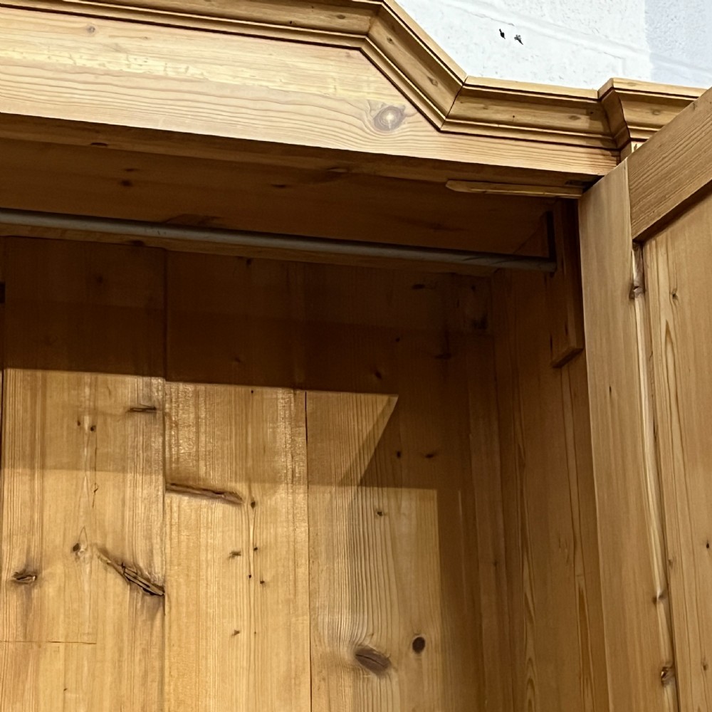 A tall Victorian pine two-door cupboard featuring field-panelled doors, turned bun feet, and a shaped bonnet top pediment. View VIII