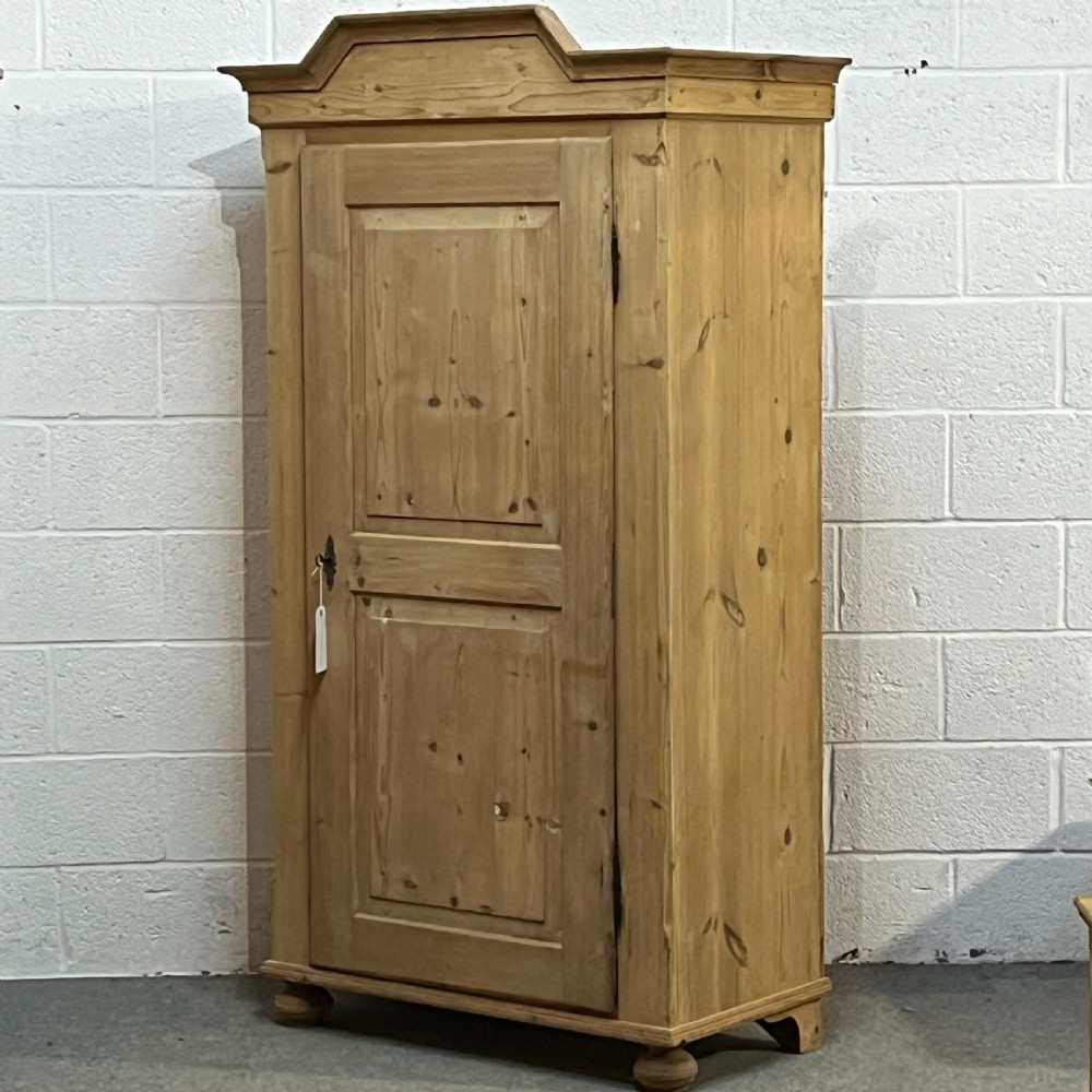 A single-door antique pine wardrobe featuring a stepped cornice, two recessed door panels, an iron key escutcheon, and turned bun feet. View II