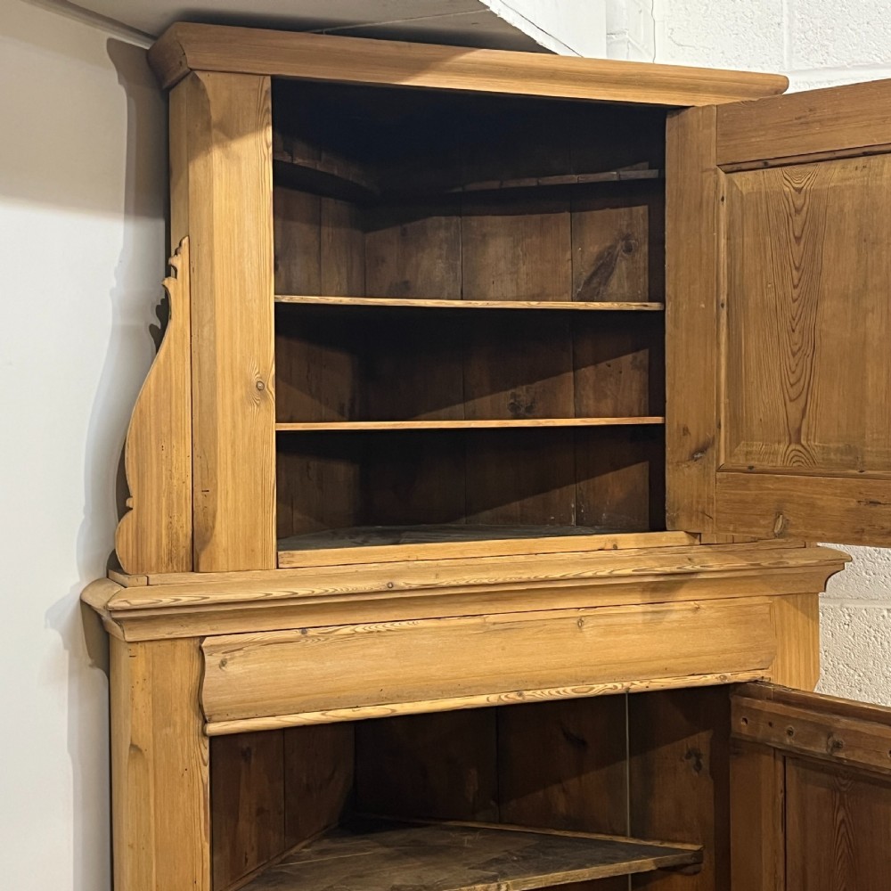 A tall two-tier antique pine corner cupboard with single panelled upper and lower doors and side scroll details. View VIII