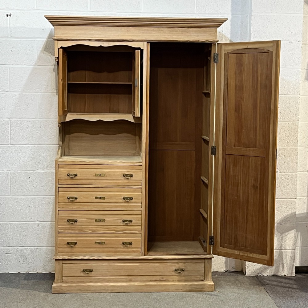 A tall antique stripped pine combination cupboard unit featuring a single long door, upper cabinet, open alcove, side drawers, and a base drawer. View II