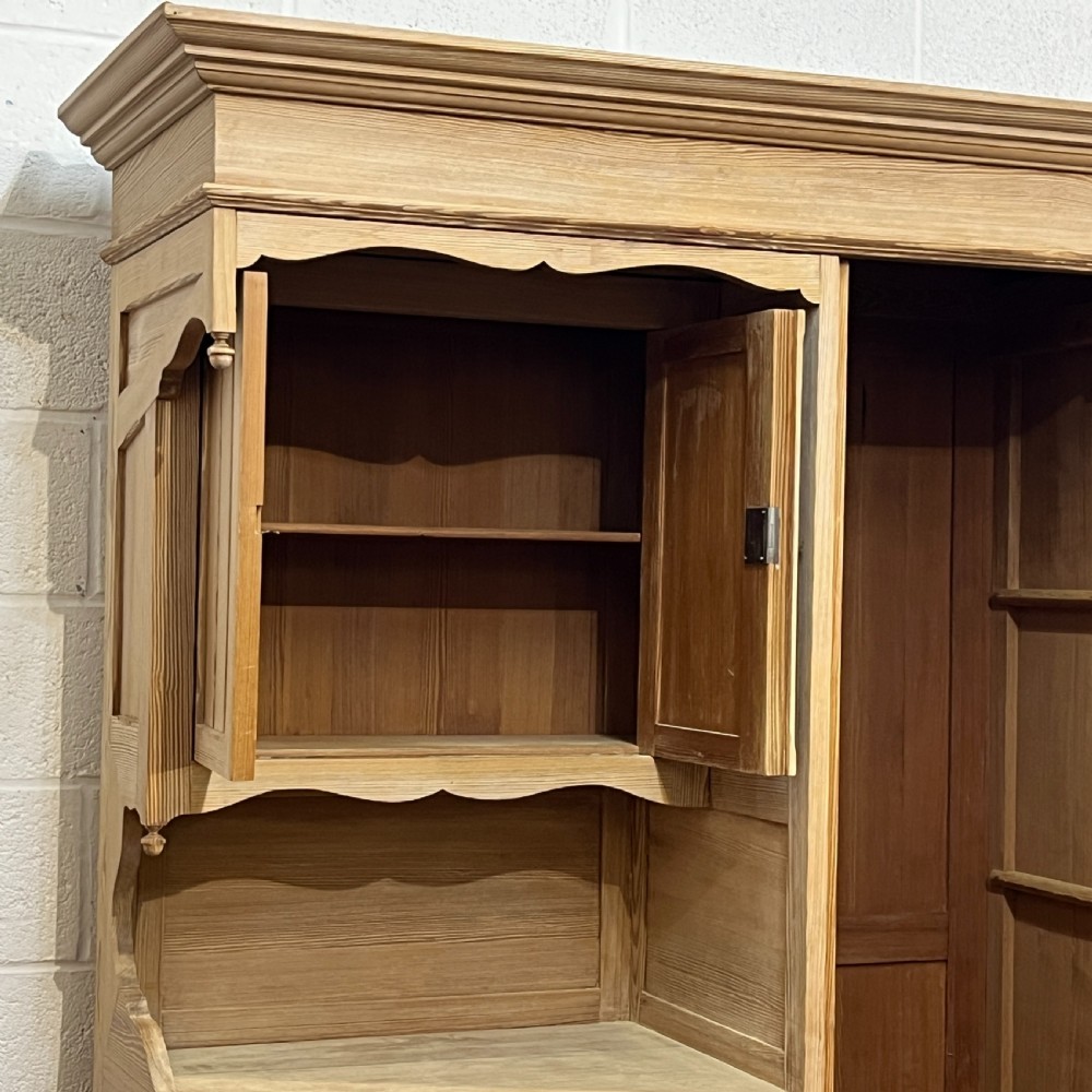 A tall antique stripped pine combination cupboard unit featuring a single long door, upper cabinet, open alcove, side drawers, and a base drawer. View III