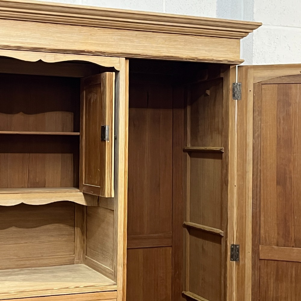 A tall antique stripped pine combination cupboard unit featuring a single long door, upper cabinet, open alcove, side drawers, and a base drawer. View V
