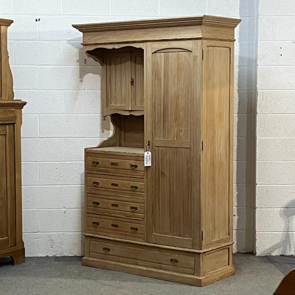 A tall antique stripped pine combination cupboard unit featuring a single long door, upper cabinet, open alcove, side drawers, and a base drawer. View VI