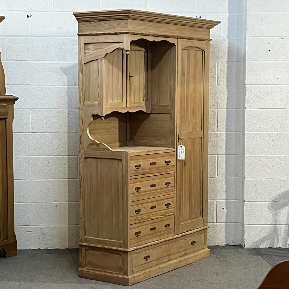 A tall antique stripped pine combination cupboard unit featuring a single long door, upper cabinet, open alcove, side drawers, and a base drawer. View VII