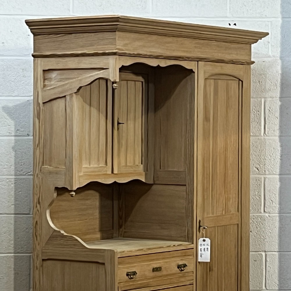 A tall antique stripped pine combination cupboard unit featuring a single long door, upper cabinet, open alcove, side drawers, and a base drawer. View VIII