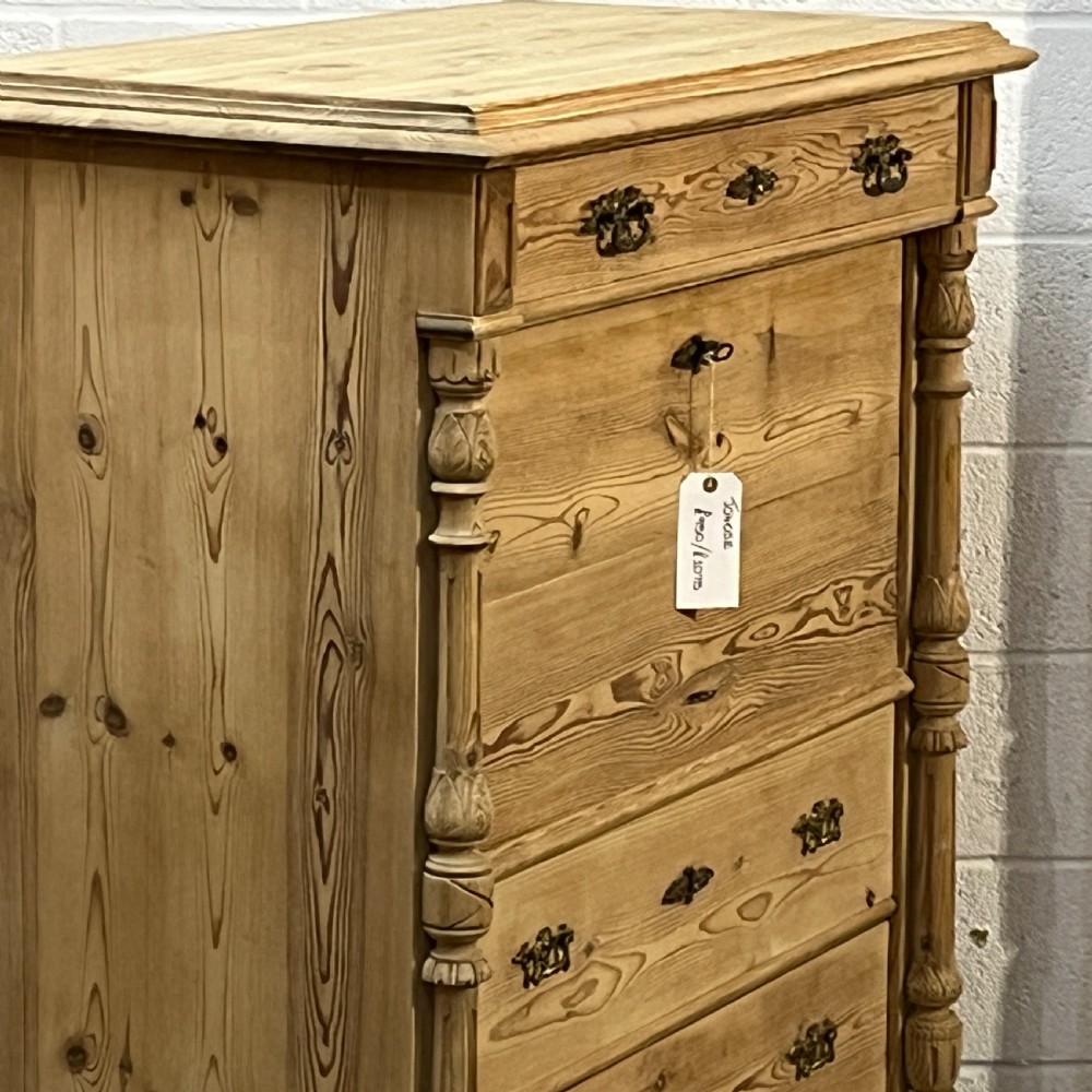 An antique pine secretaire desk featuring a fall-front writing compartment above multiple drawers, decorated with turned side columns and dark metal handles. View VI