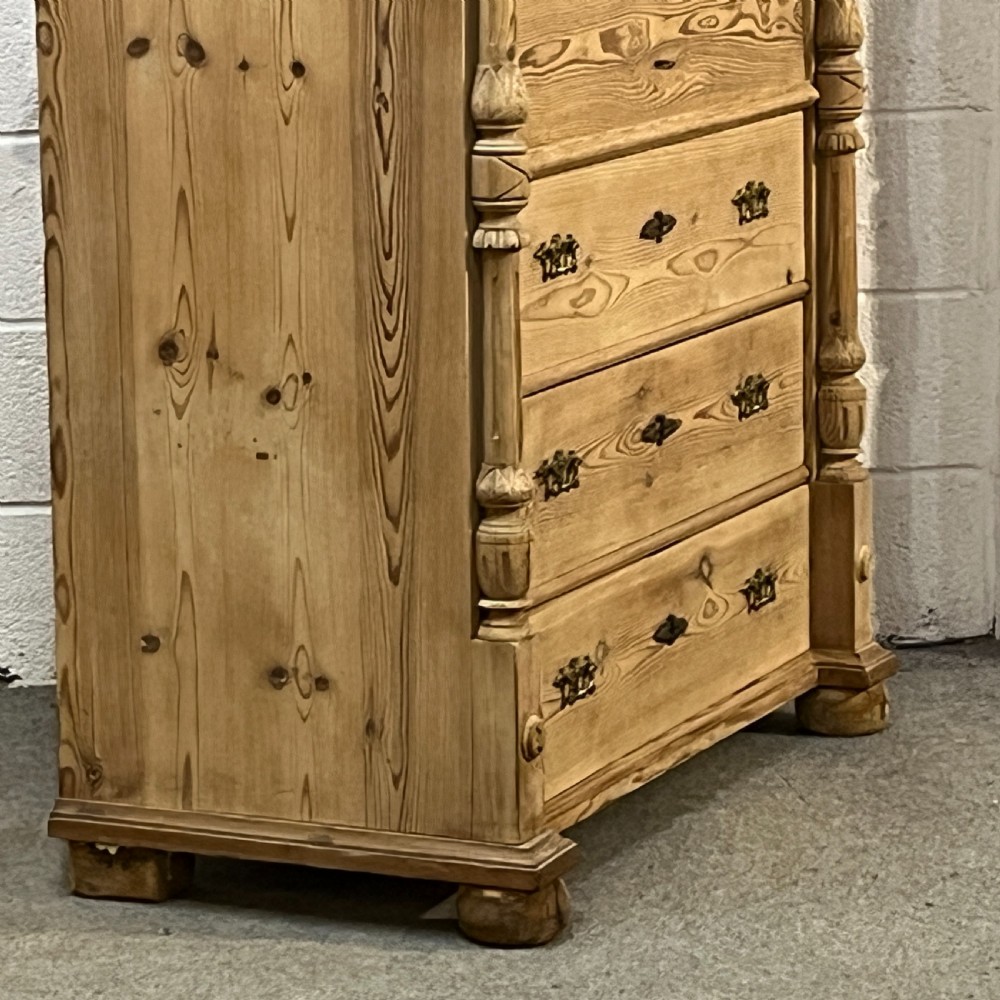 An antique pine secretaire desk featuring a fall-front writing compartment above multiple drawers, decorated with turned side columns and dark metal handles. View VII