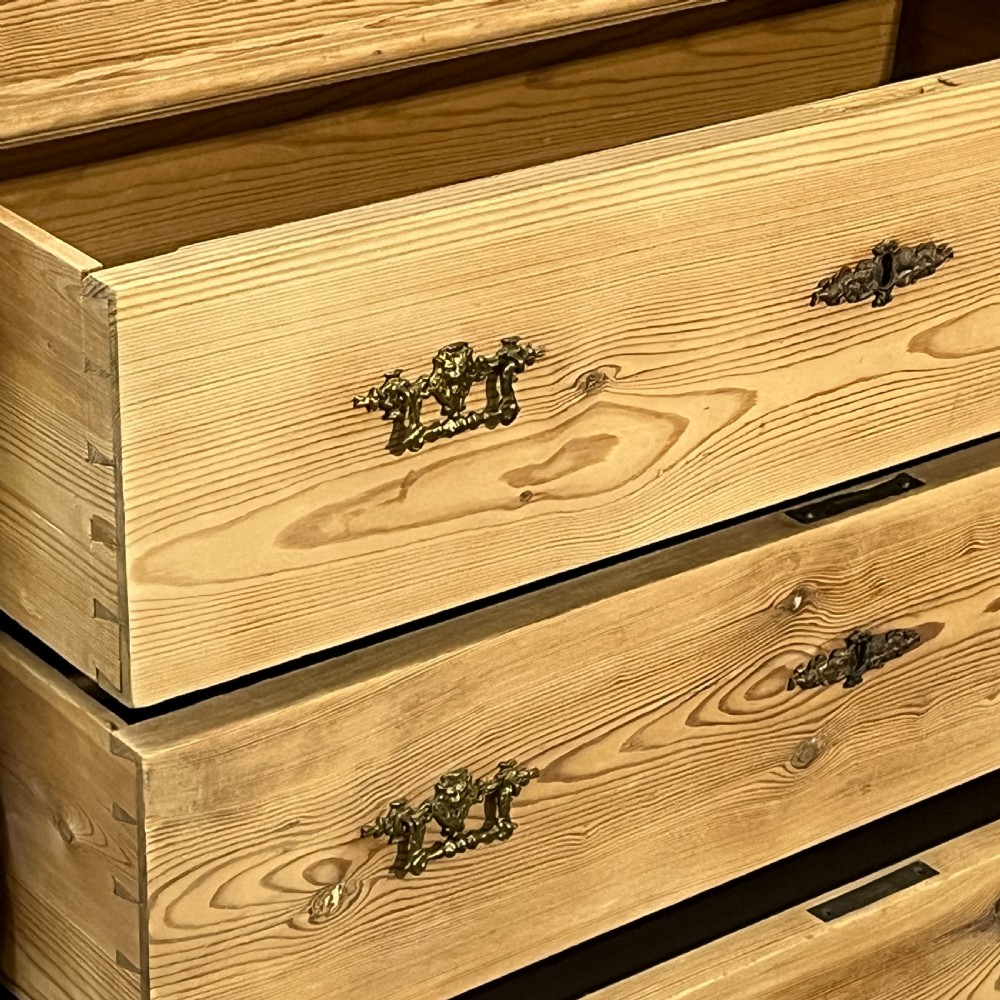 An antique pine secretaire desk featuring a fall-front writing compartment above multiple drawers, decorated with turned side columns and dark metal handles. View X