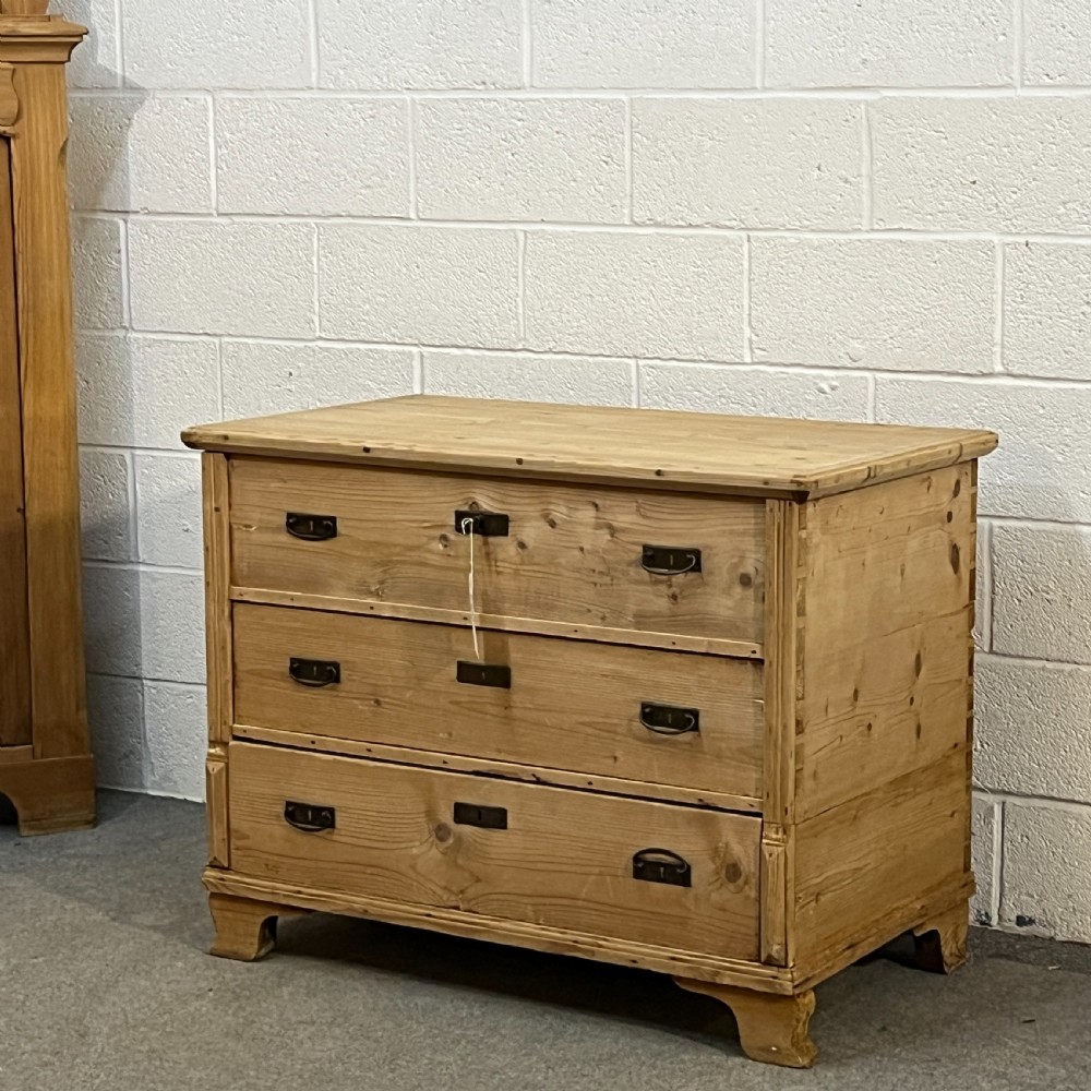 A large natural pine mule chest featuring an open hinged lid above lower drawers with dark metal pull handles and bracket feet. View VI
