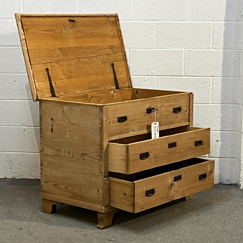 A large natural pine mule chest featuring an open hinged lid above lower drawers with dark metal pull handles and bracket feet. View VII