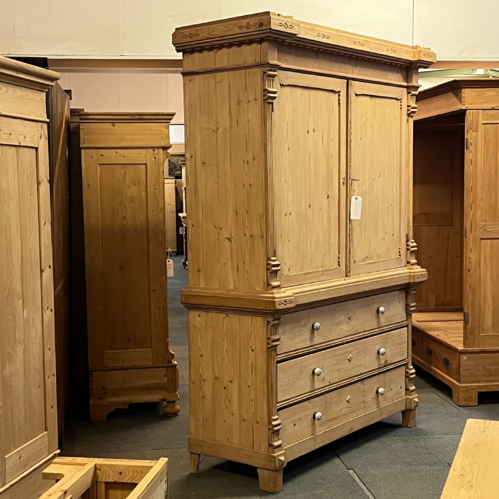 A tall nineteenth-century Dutch pine linen press featuring a twin-panelled upper cupboard set over a lower base of three wide drawers with turned knobs. View II