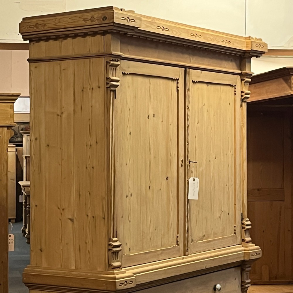 A tall nineteenth-century Dutch pine linen press featuring a twin-panelled upper cupboard set over a lower base of three wide drawers with turned knobs. View V