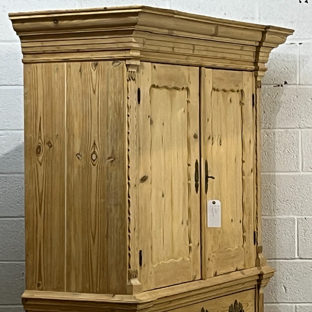 A tall two-part natural pine linen press featuring a double-door top cupboard over three drawers with brass drop handles. View III