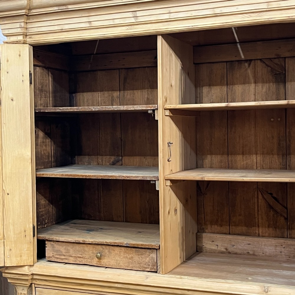 A tall two-part natural pine linen press featuring a double-door top cupboard over three drawers with brass drop handles. View VIII