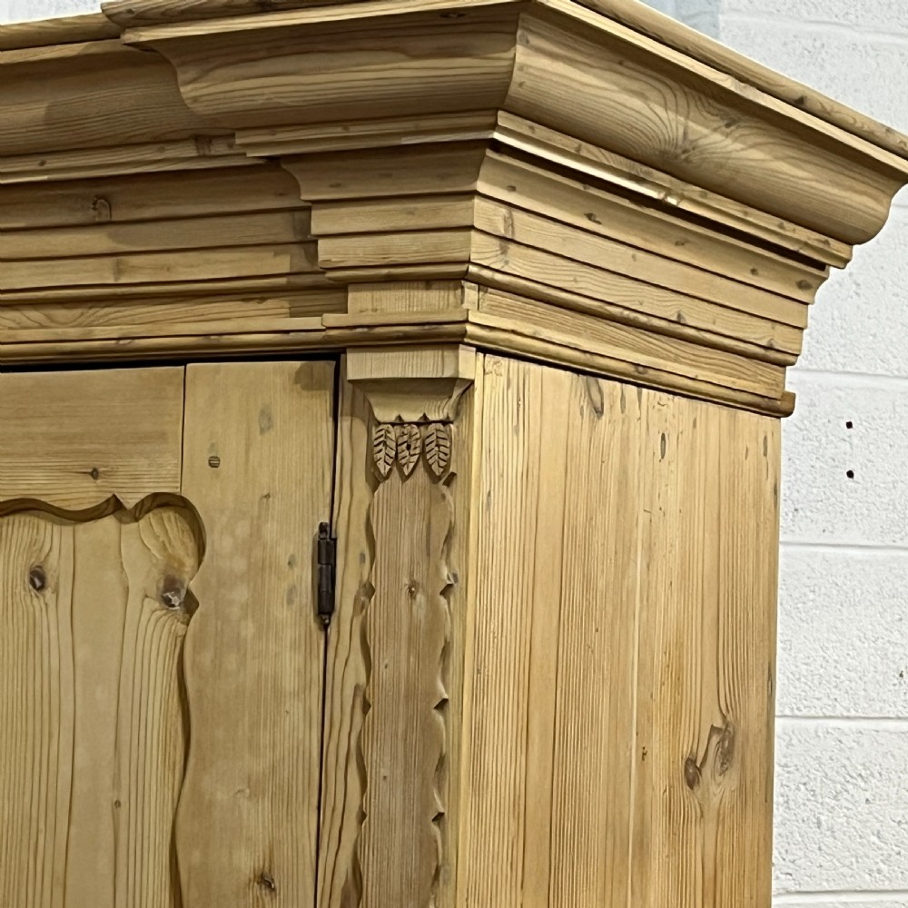 A tall two-part natural pine linen press featuring a double-door top cupboard over three drawers with brass drop handles. View XIV