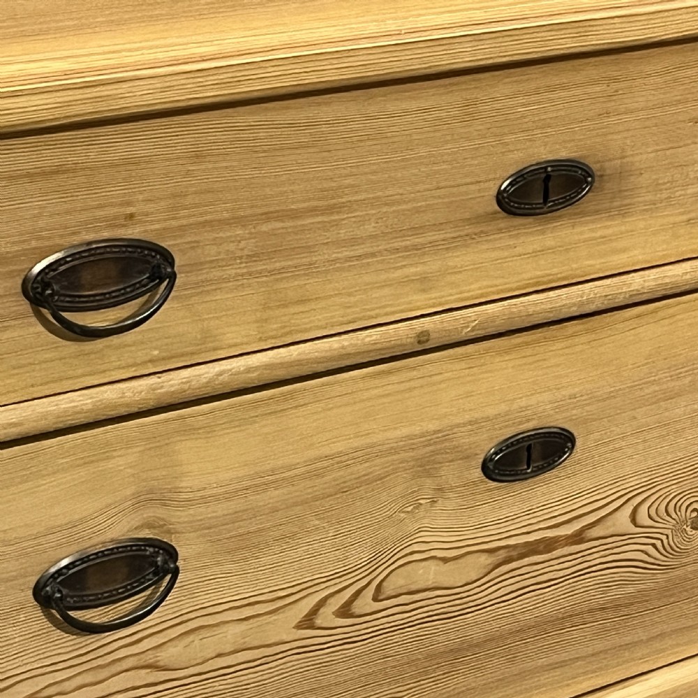 A tall antique stripped pine secretaire bureau featuring a upper fall-front writing flap above three long drawers with brass handles and a carved lower apron. View VII