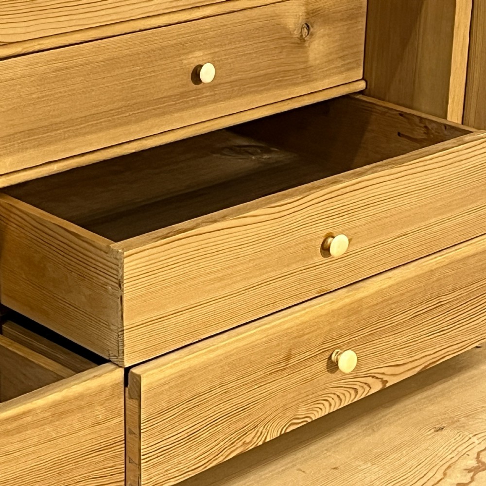 A tall antique stripped pine secretaire bureau featuring a upper fall-front writing flap above three long drawers with brass handles and a carved lower apron. View X
