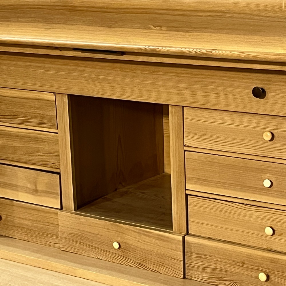 A tall antique stripped pine secretaire bureau featuring a upper fall-front writing flap above three long drawers with brass handles and a carved lower apron. View XI