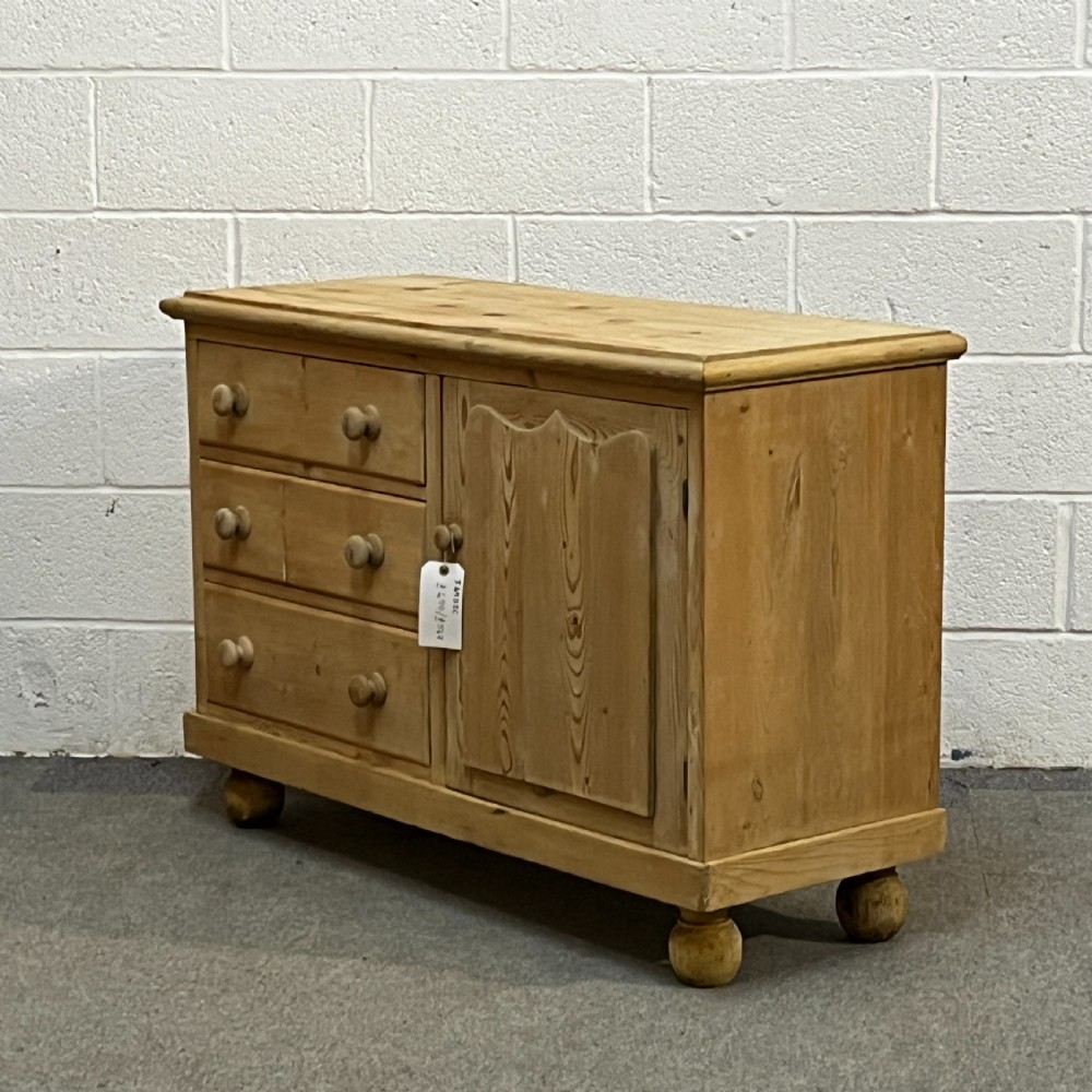 A small Edwardian pine chiffonier featuring three drawers on the left with turned wooden knob handles, a single panelled cupboard door on the right, and rounded bun feet. View II