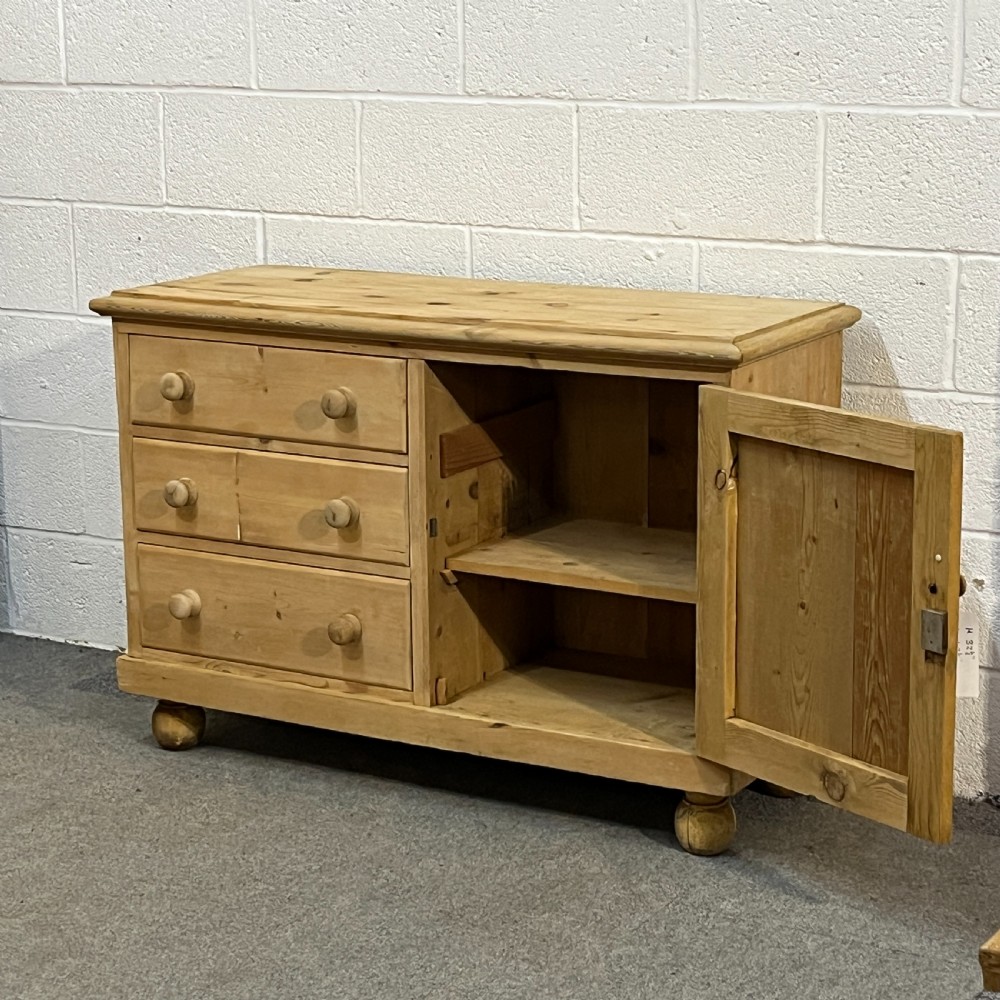 A small Edwardian pine chiffonier featuring three drawers on the left with turned wooden knob handles, a single panelled cupboard door on the right, and rounded bun feet. View IV