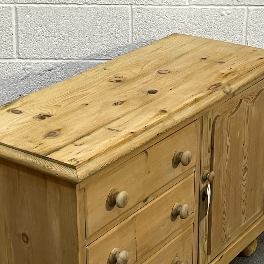 A small Edwardian pine chiffonier featuring three drawers on the left with turned wooden knob handles, a single panelled cupboard door on the right, and rounded bun feet. View VI