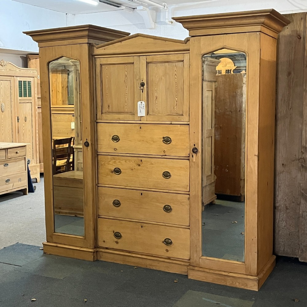 A large Victorian pine combination wardrobe featuring a central chest of drawers and upper cupboard, flanked by two full-length mirrored side doors with arched tops. View II