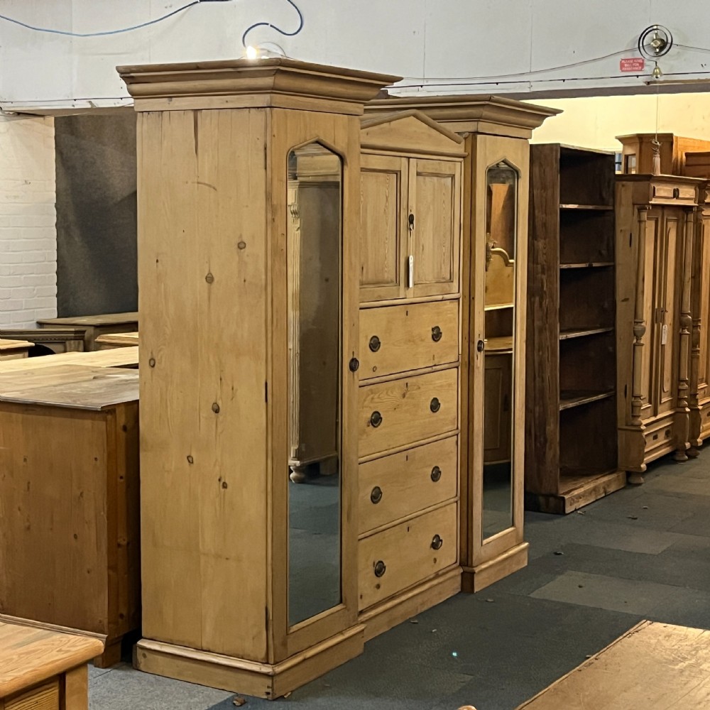 A large Victorian pine combination wardrobe featuring a central chest of drawers and upper cupboard, flanked by two full-length mirrored side doors with arched tops. View III