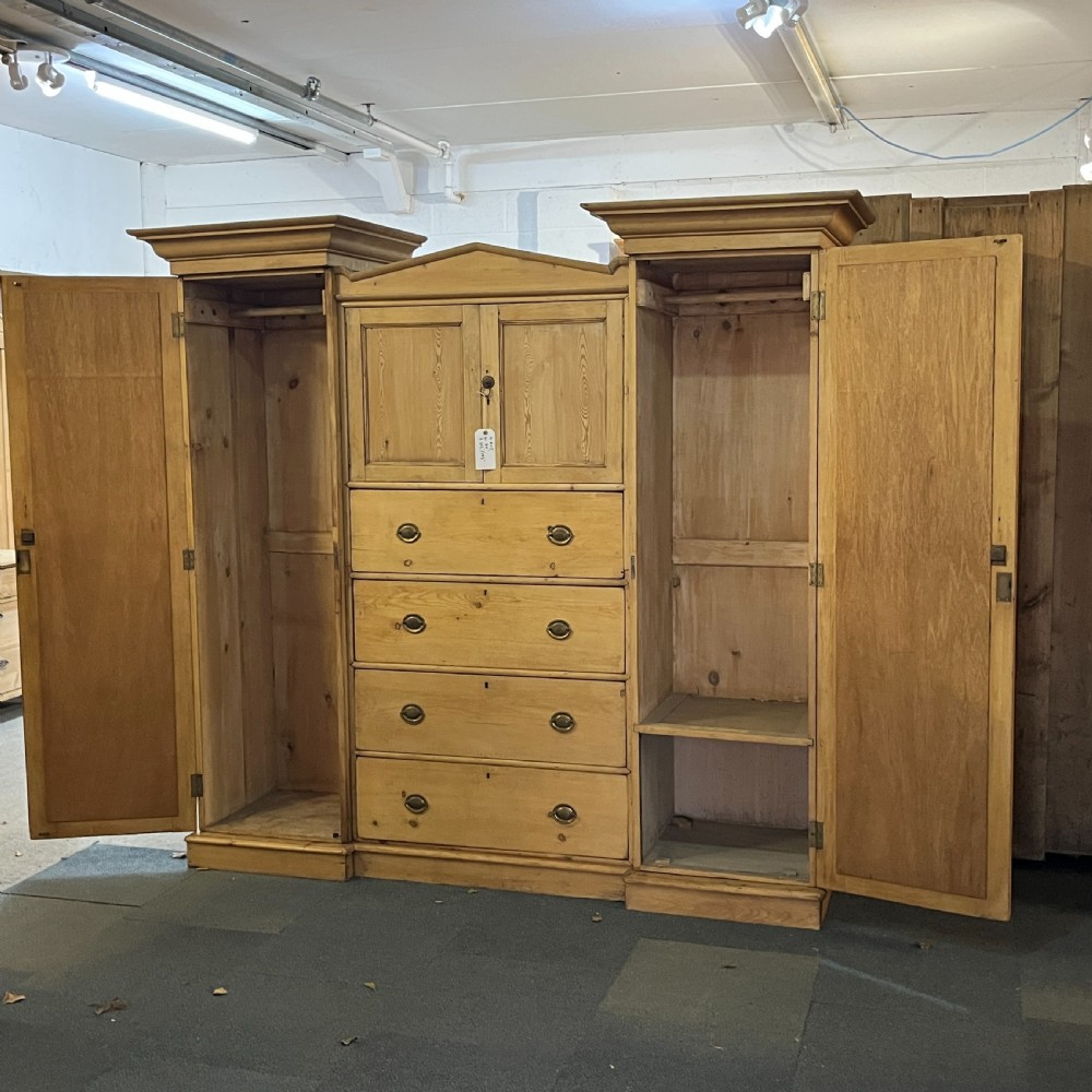 A large Victorian pine combination wardrobe featuring a central chest of drawers and upper cupboard, flanked by two full-length mirrored side doors with arched tops. View IV