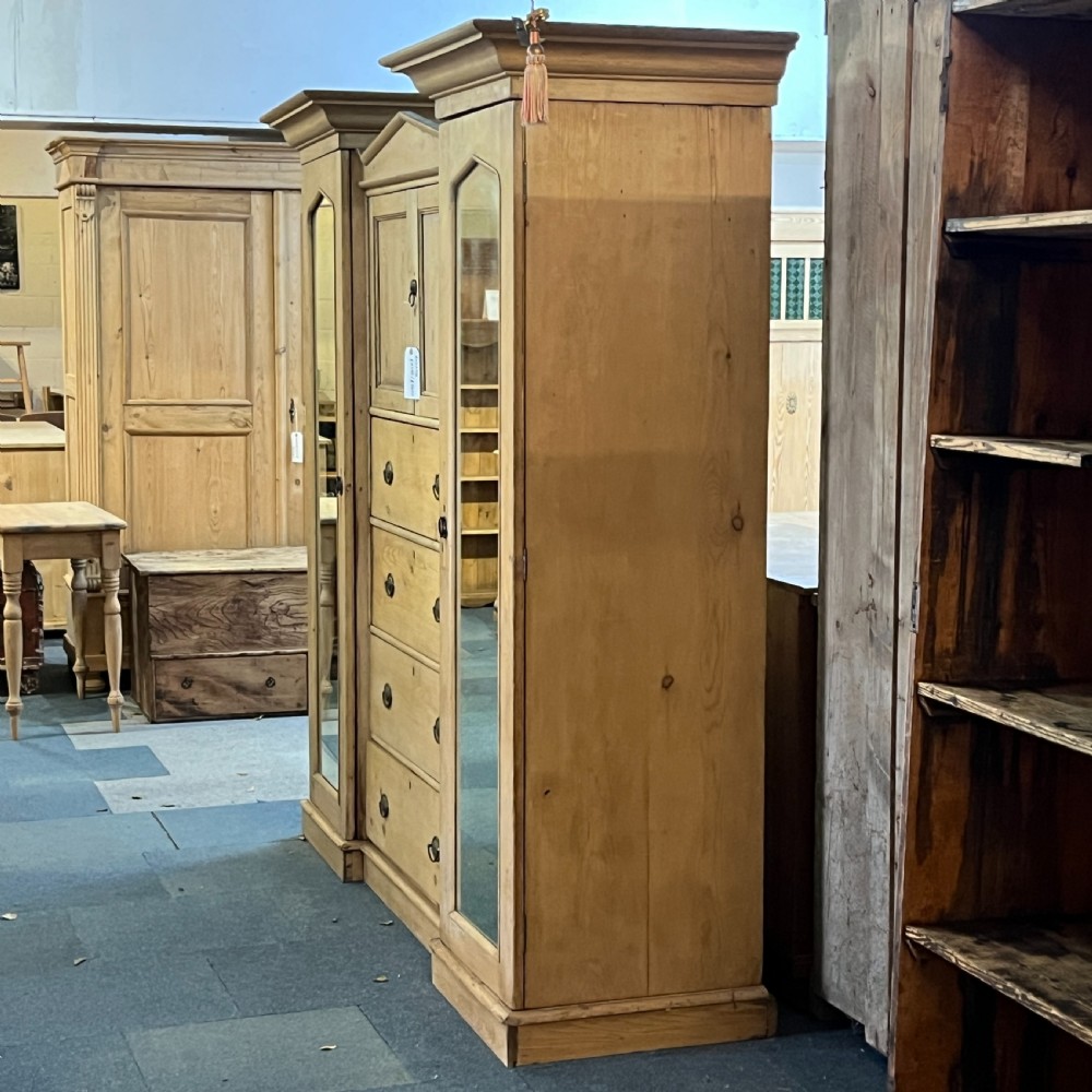 A large Victorian pine combination wardrobe featuring a central chest of drawers and upper cupboard, flanked by two full-length mirrored side doors with arched tops. View VII