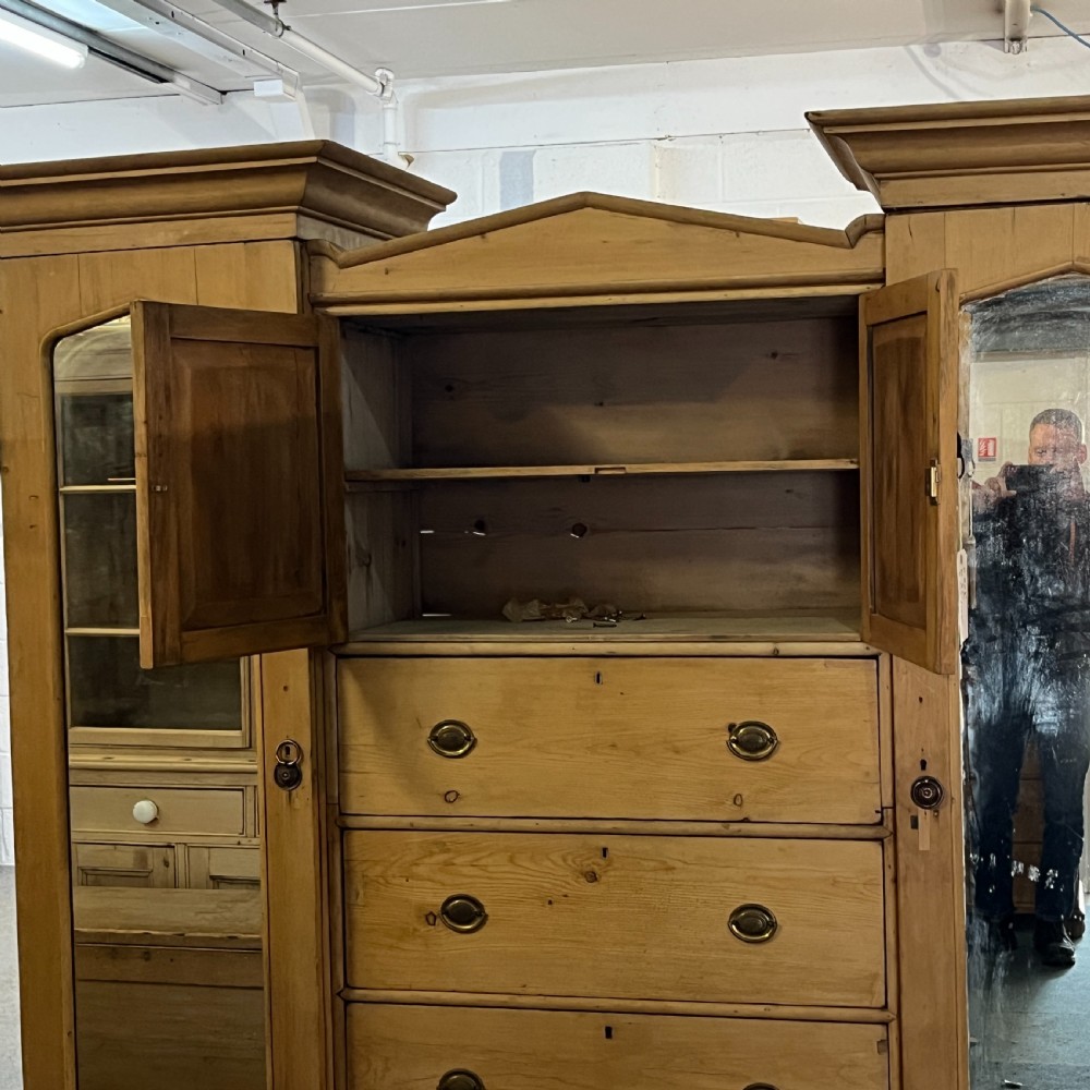A large Victorian pine combination wardrobe featuring a central chest of drawers and upper cupboard, flanked by two full-length mirrored side doors with arched tops. View VIII