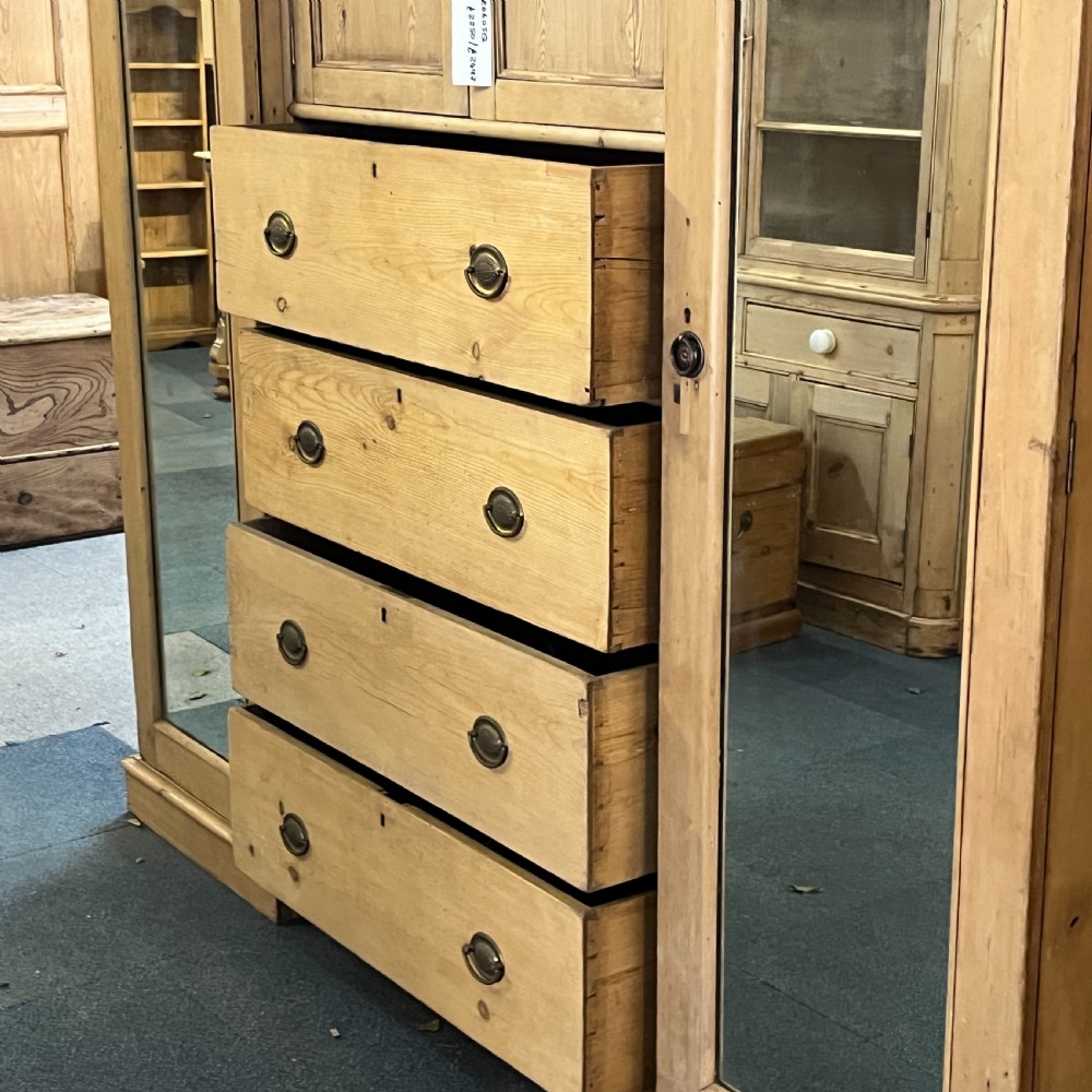 A large Victorian pine combination wardrobe featuring a central chest of drawers and upper cupboard, flanked by two full-length mirrored side doors with arched tops. View IX