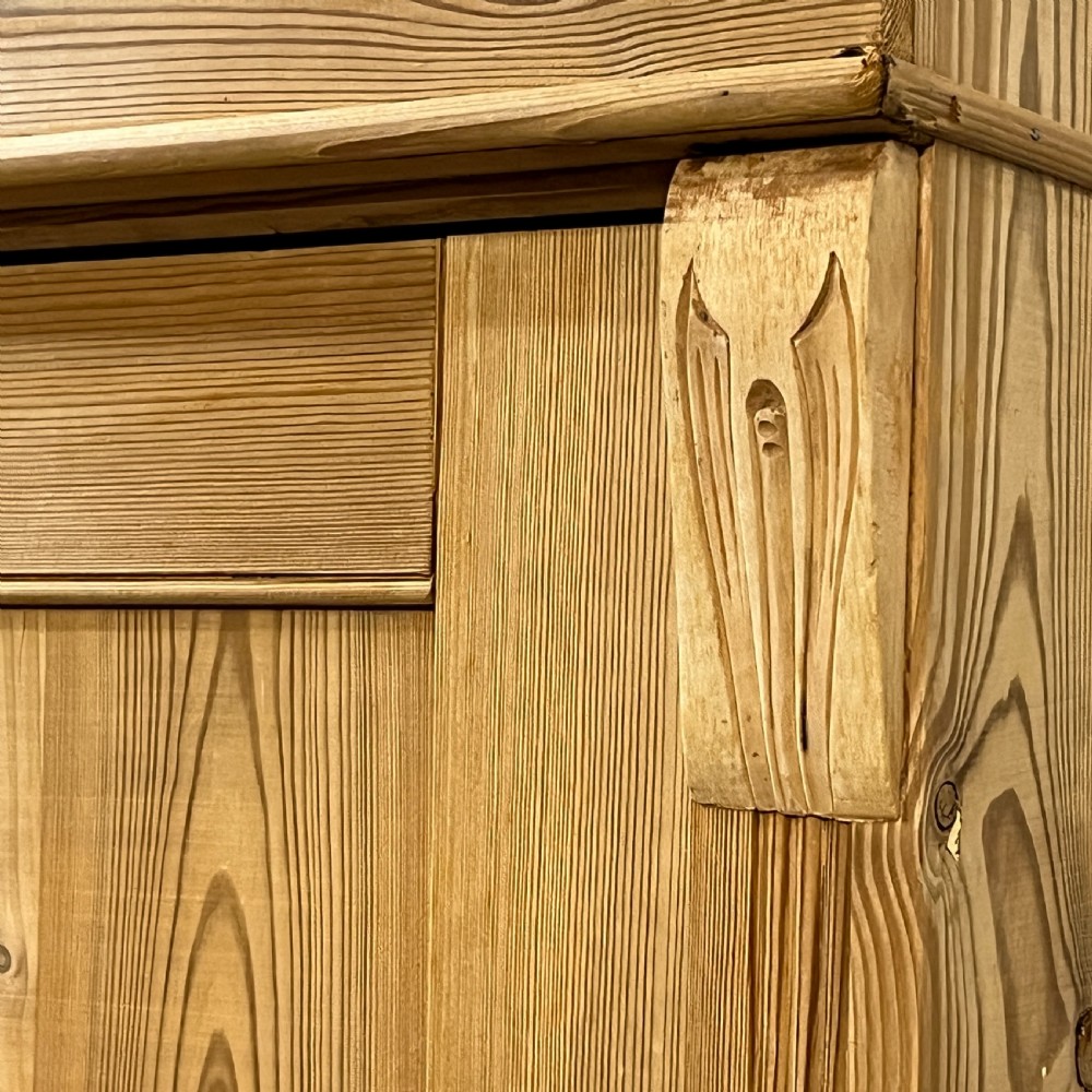 An antique pine wardrobe with two panelled doors, a single bottom drawer, turned bun feet, and a moulded top cornice. View XI
