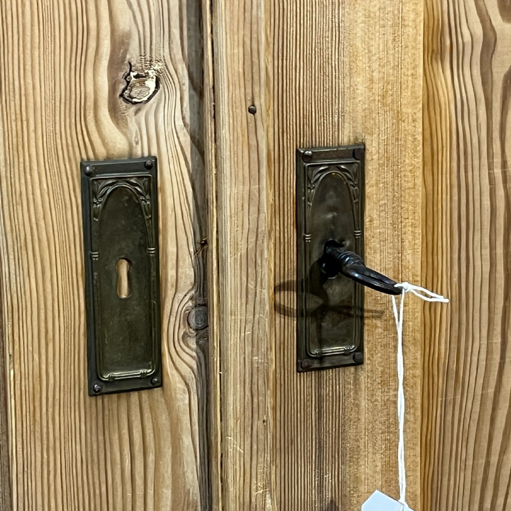 An antique pine wardrobe with two panelled doors, a single bottom drawer, turned bun feet, and a moulded top cornice. View XII