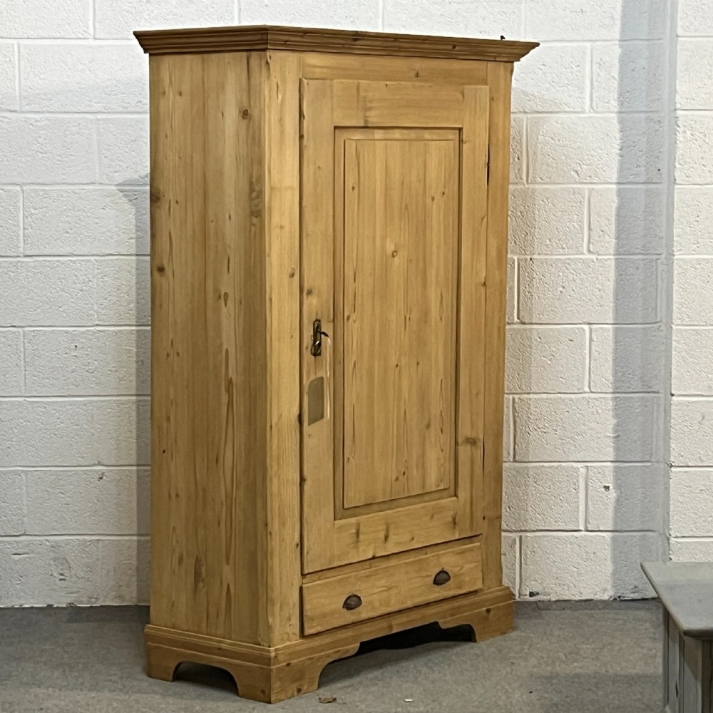 A single-door antique pine wardrobe featuring a central recessed panel, a bottom drawer with shell cup handles, and a moulded top cornice. View III