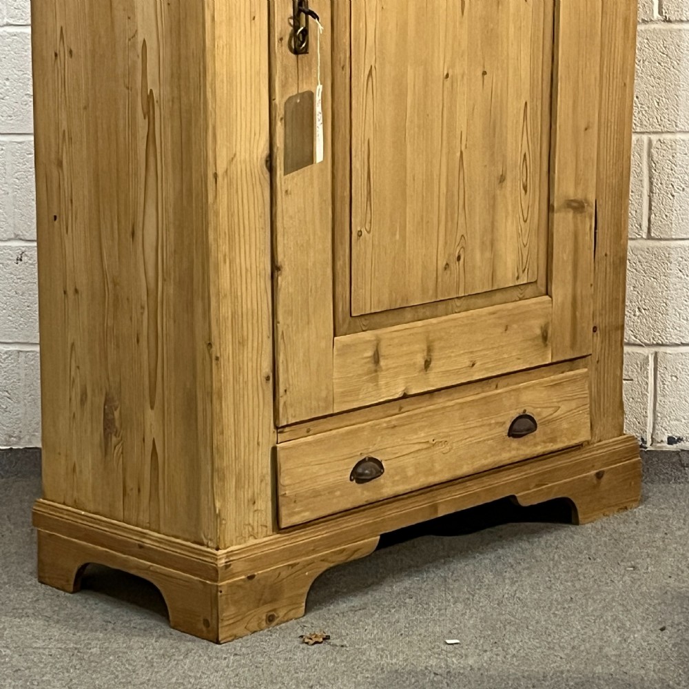 A single-door antique pine wardrobe featuring a central recessed panel, a bottom drawer with shell cup handles, and a moulded top cornice. View V