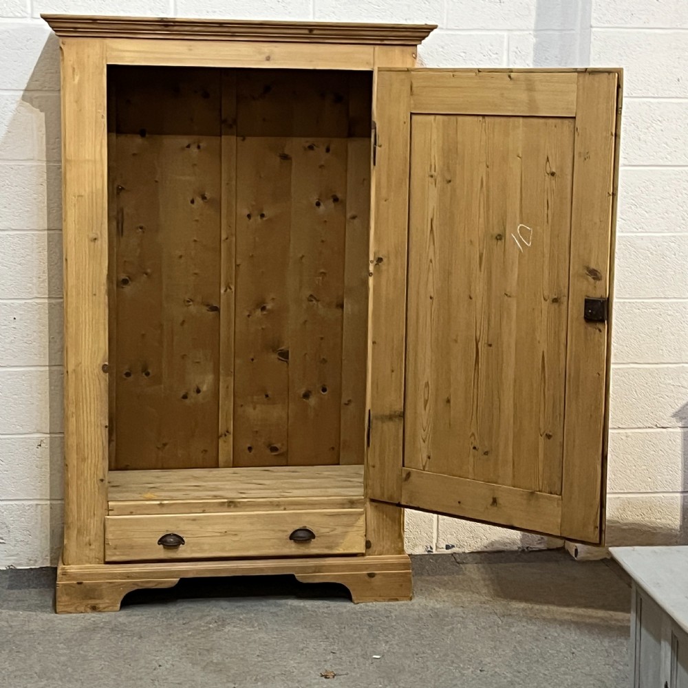 A single-door antique pine wardrobe featuring a central recessed panel, a bottom drawer with shell cup handles, and a moulded top cornice. View VI