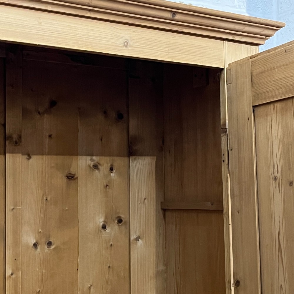 A single-door antique pine wardrobe featuring a central recessed panel, a bottom drawer with shell cup handles, and a moulded top cornice. View VII