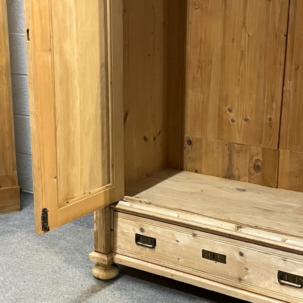 A stripped pine wardrobe featuring carved panel doors with Art Nouveau motifs, a lower drawer with brass handles, and turned bun feet. View XI