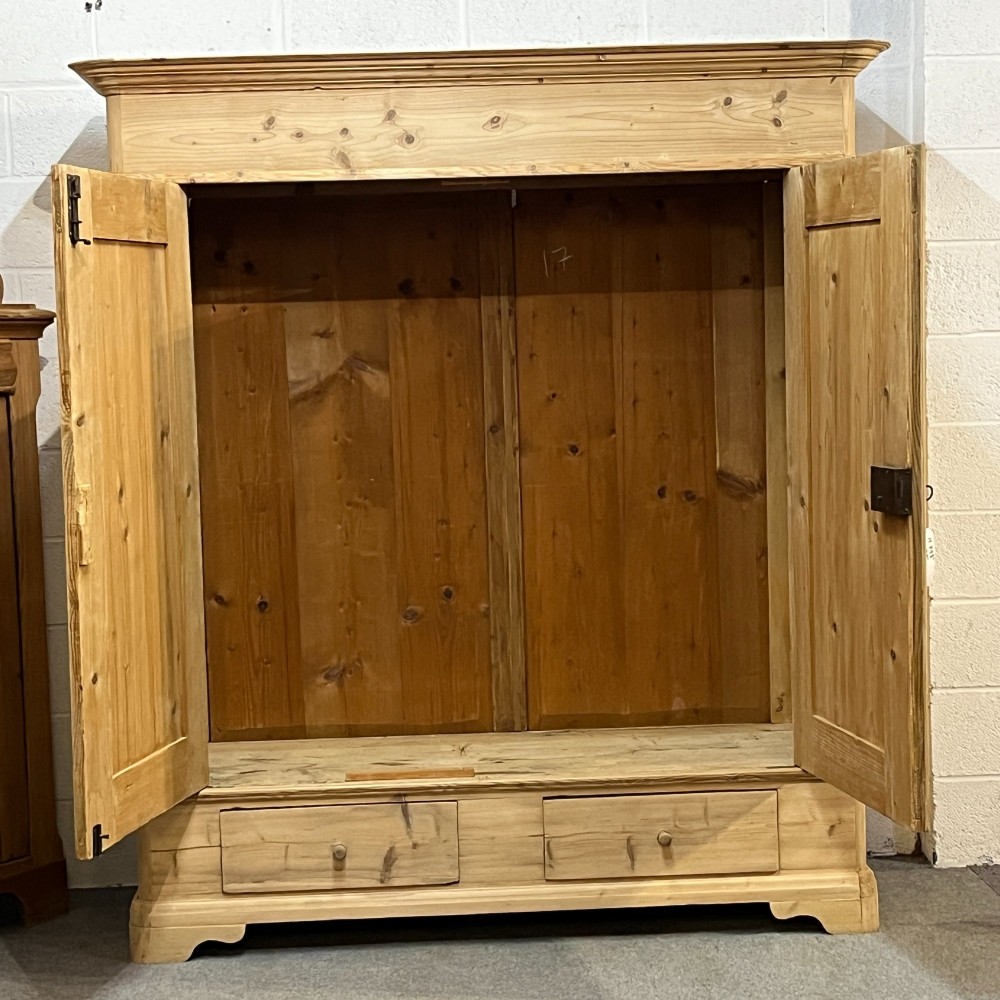 A large Victorian pine double wardrobe featuring fielded panel doors, iron escutcheons, and two base drawers on a plinth foundation. View VII