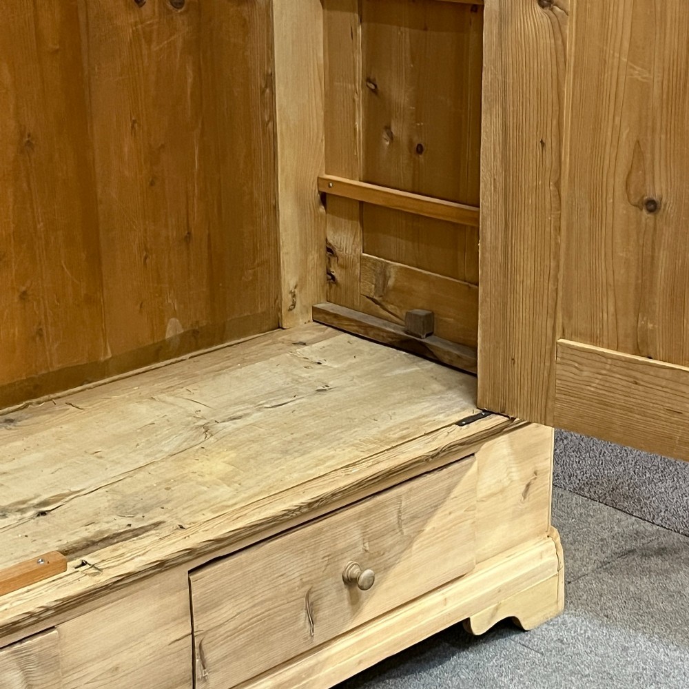 A large Victorian pine double wardrobe featuring fielded panel doors, iron escutcheons, and two base drawers on a plinth foundation. View VIII