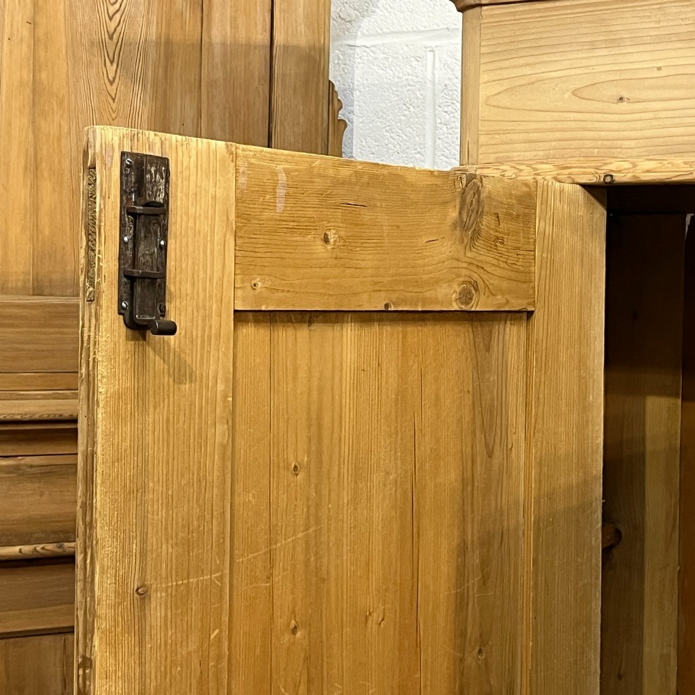 A large Victorian pine double wardrobe featuring fielded panel doors, iron escutcheons, and two base drawers on a plinth foundation. View X
