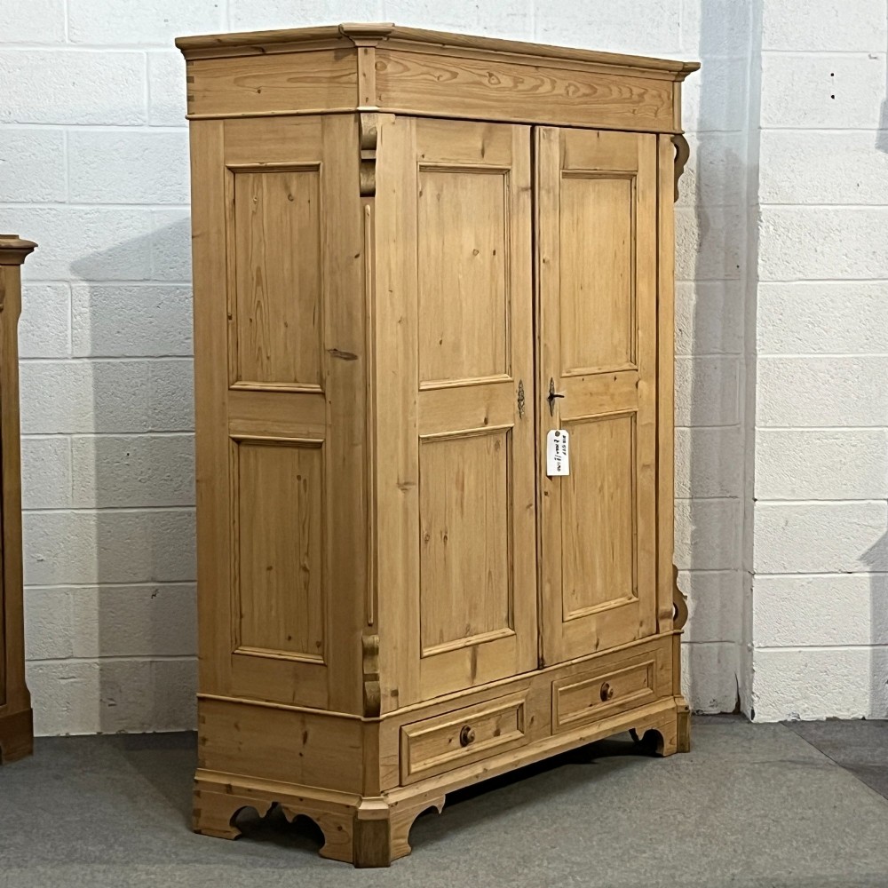 A large antique pine double wardrobe featuring panelled doors, two bottom drawers with turned handles, and a moulded top cornice. View III