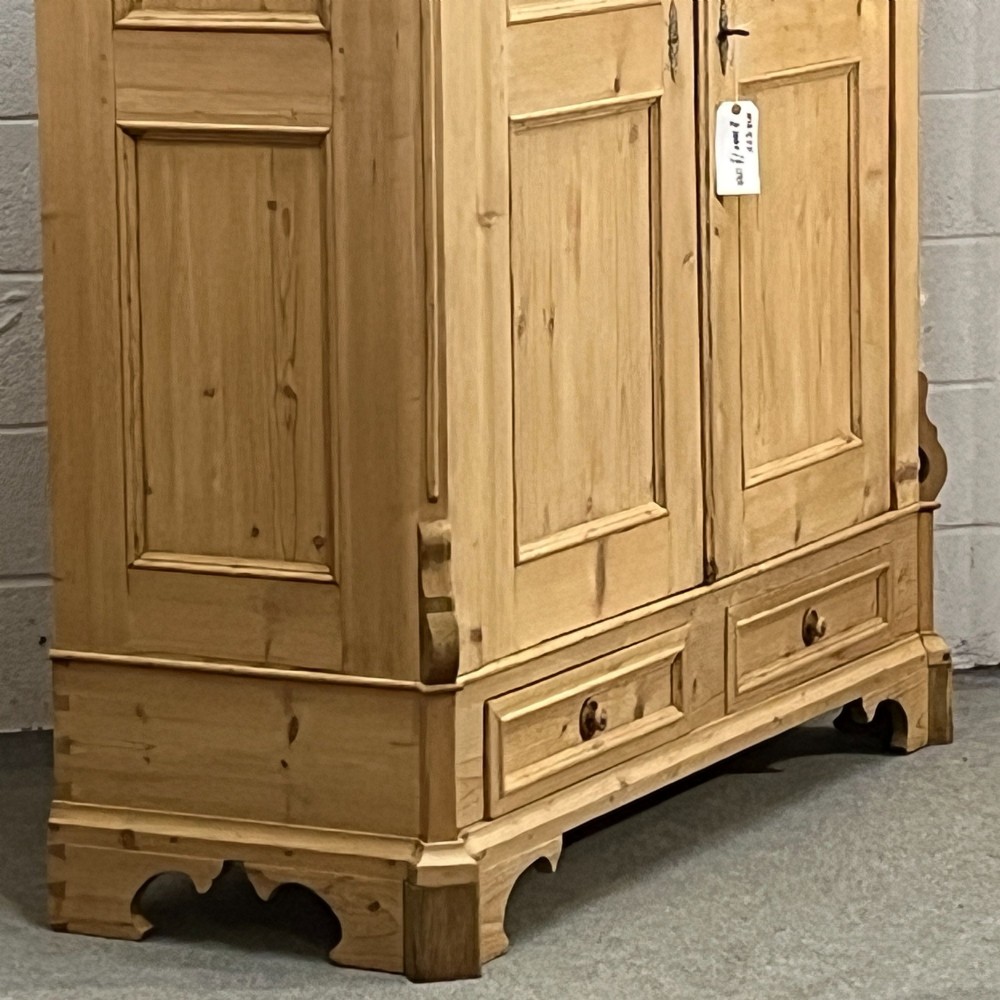 A large antique pine double wardrobe featuring panelled doors, two bottom drawers with turned handles, and a moulded top cornice. View V