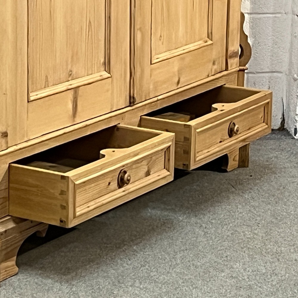 A large antique pine double wardrobe featuring panelled doors, two bottom drawers with turned handles, and a moulded top cornice. View VII