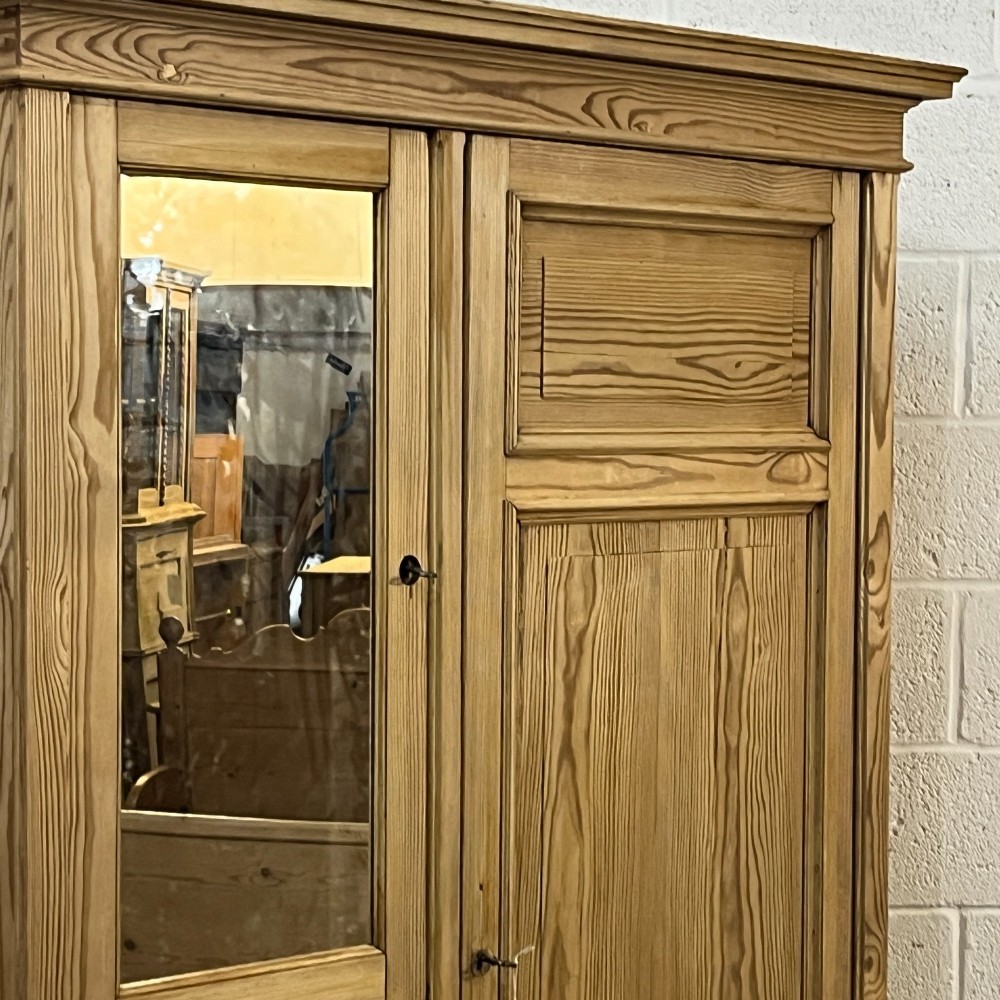 A freestanding 1930s pine compactum wardrobe featuring a upper mirror above four drawers on the left and a tall panelled door on the right. View VI