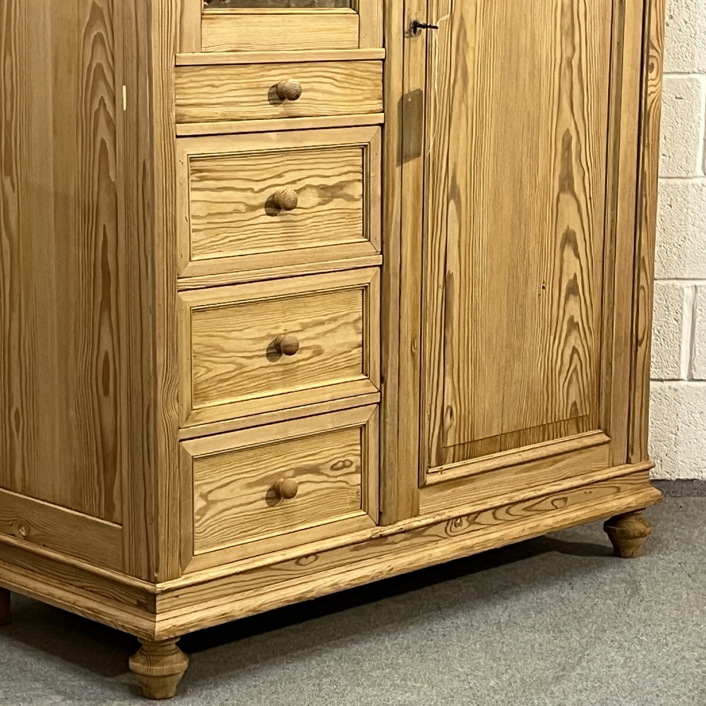 A freestanding 1930s pine compactum wardrobe featuring a upper mirror above four drawers on the left and a tall panelled door on the right. View VII