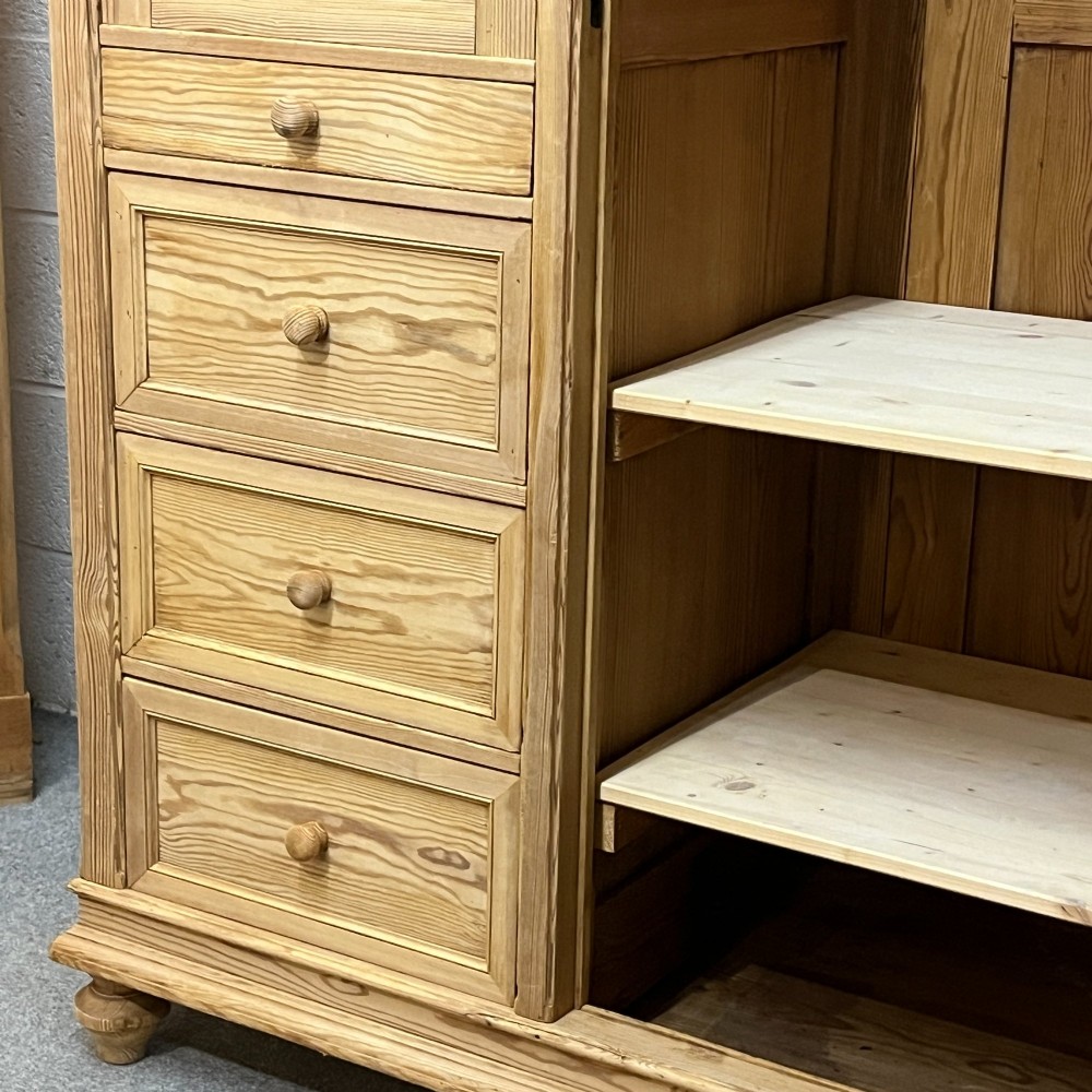 A freestanding 1930s pine compactum wardrobe featuring a upper mirror above four drawers on the left and a tall panelled door on the right. View VIII