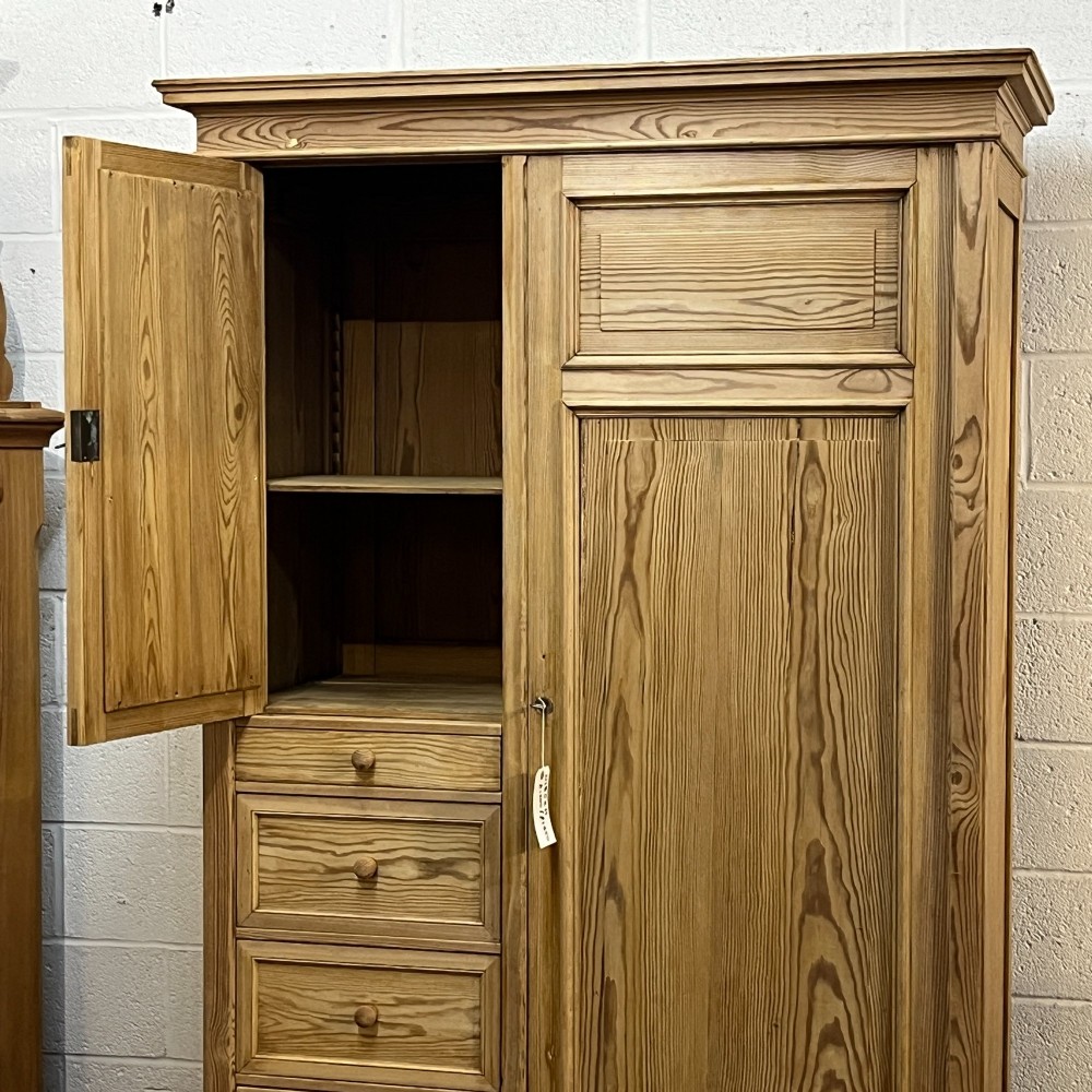 A freestanding 1930s pine compactum wardrobe featuring a upper mirror above four drawers on the left and a tall panelled door on the right. View IX
